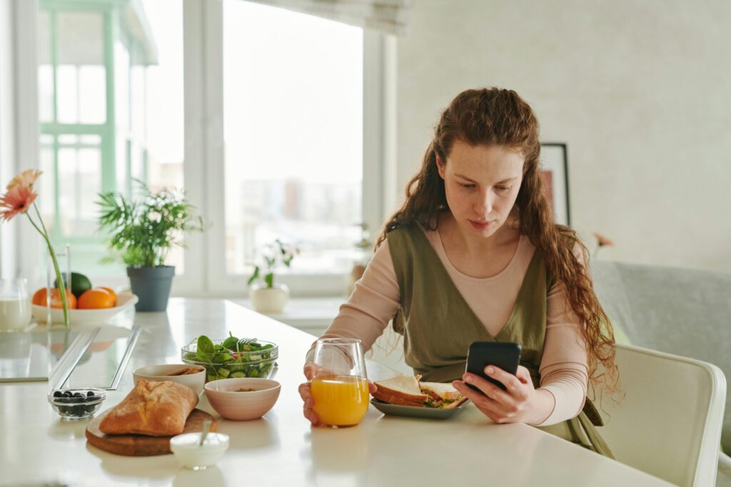 pexels-photo-7485100-7485100 Pregnant woman at breakfast table browsing on smartphone while having a healthy meal indoors.