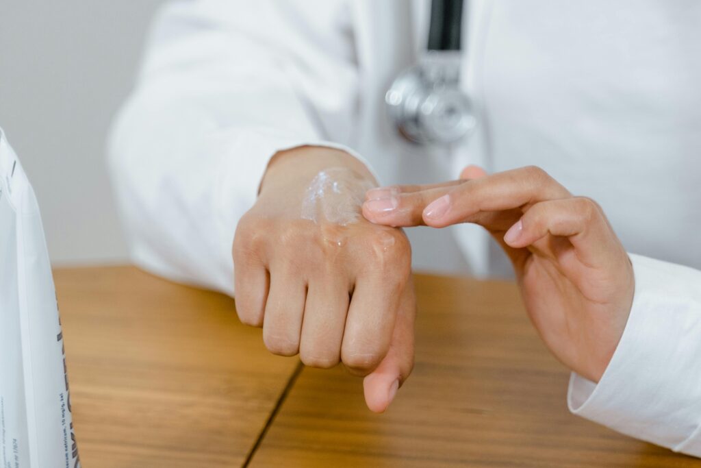 pexels-photo-8376308-8376308 Close-up of a doctor applying lotion on their hand, focusing on skincare.